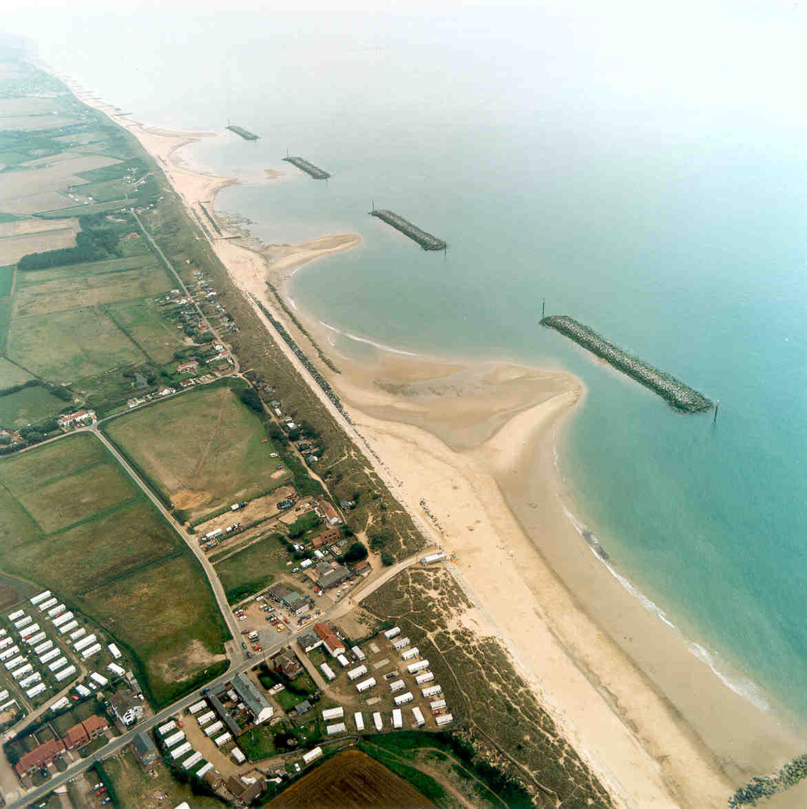 Aerial photograph of shore-parallel breakwaters that have caused increased levels of sand accumulation along the coast.